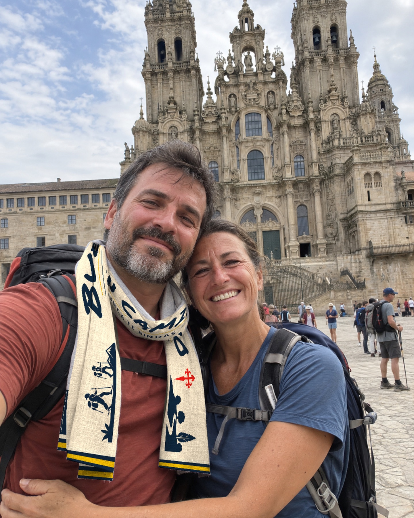 Dos peregrinos con la bufanda azul y crema delante de la Catedral