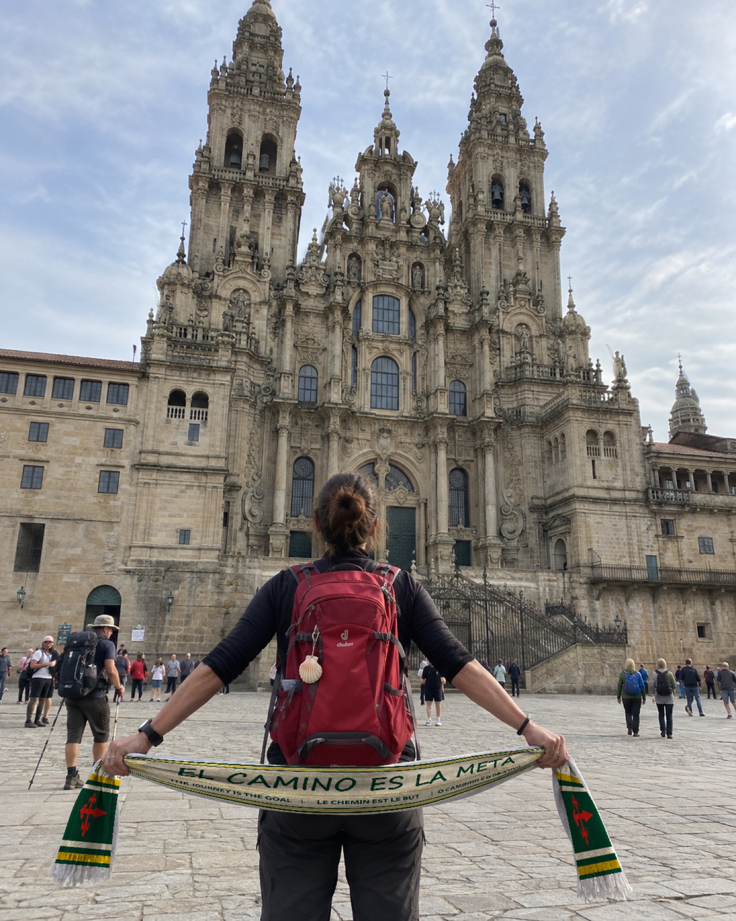 Peregrino de espaldas muestra la bufanda verde ante la Catedral