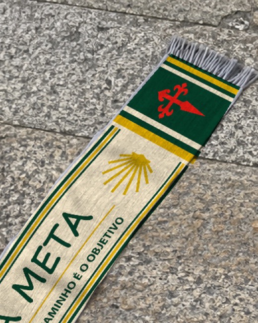 Primer plano de la cruz roja y la concha dorada sobre la bufanda verde y oro